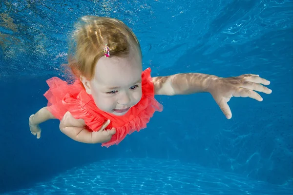 little girl learns to swim underwater in the pool