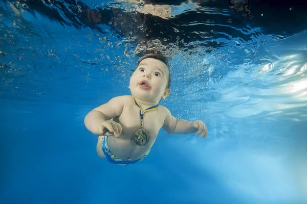 little boy learns to swim underwater in the pool