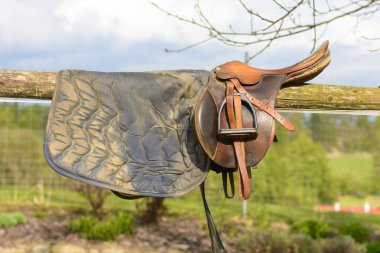 Deri kovboy eyer korkuluk üzerinde asılı