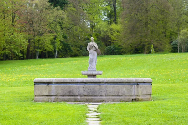 Каменный фонтан со статуей в центре замкового парка — стоковое фото
