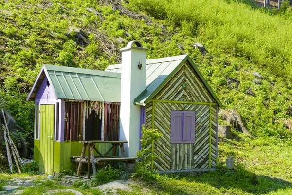 Small wooden cottage under the hill in the woods. Cottage built of natural materials.