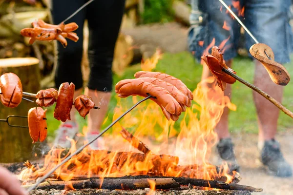 Worstjes grillen boven een kampvuur in het bos — Stockfoto