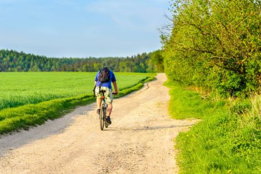 Tozlu bir yol günbatımında sürme bir bisikletçi
