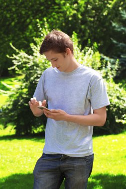 Etkileşimli genç adam tarafından bir parkta bir akıllı telefon iletişim.