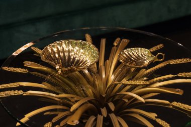Golden seashells ashtray on top of glass transparent table.