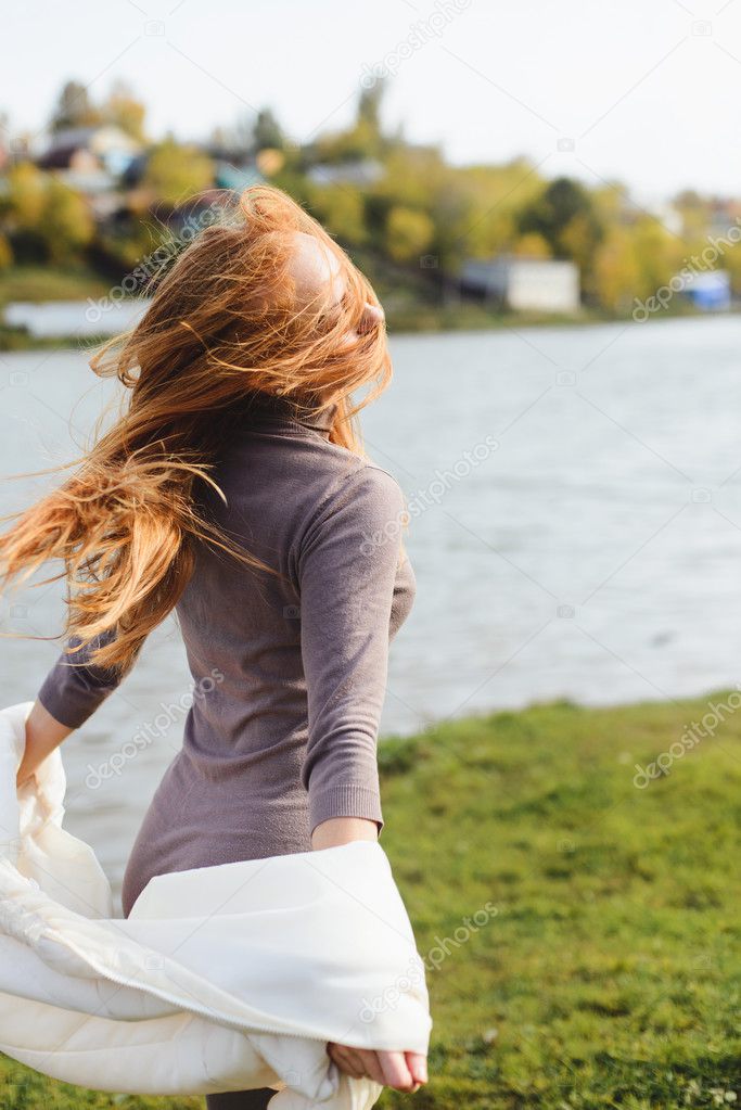 Redhead young woman walking in autumn park near water