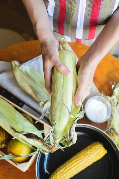 Верхний вид женщины готовит кукурузу для приготовления пищи в миске — стоковое фото