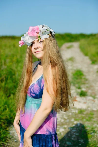 Fille avec une couronne de fleurs sur la tête dans le champ — Photo