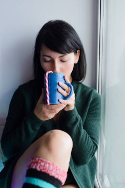 Pencere kenarında içki ve çizgili şeker kamışlı bir kadın.