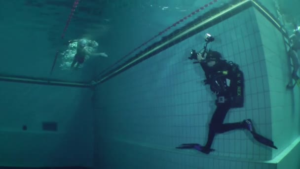 Podwodny fotograf strzela dziewczyna umiejących pływać w basenie. — Wideo stockowe