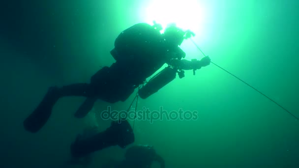 Divers on the background of a water surface and a solar disk. — Stock Video