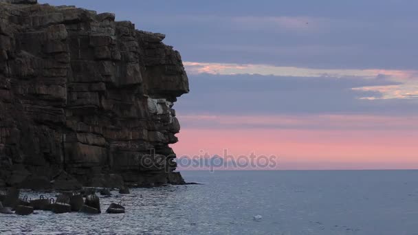 Klippiga kust cape mot bakgrund av en gryning rosa himmel. — Stockvideo