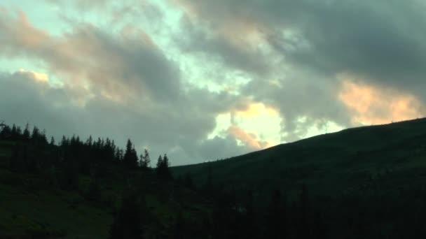 Nuvens iluminadas pelo pôr do sol sobre os cumes das montanhas . — Vídeo de Stock