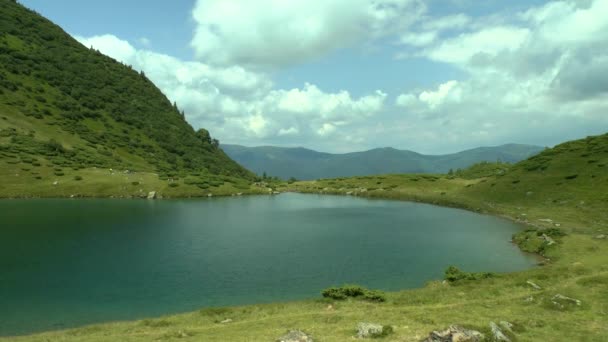 Lago limpio sobre un telón de fondo de picos de montaña y un cielo nublado . — Vídeos de Stock