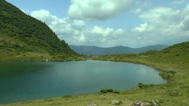 Paisagem pitoresca: em primeiro plano - lago claro, na cadeia montesa traseira e nuvens . — Vídeo de Stock