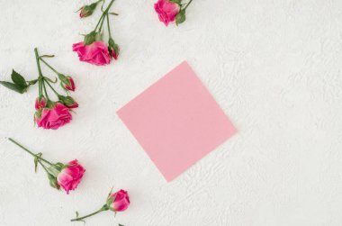 Ahşap beyaz arka planda güller ve pembe boş mesaj kartı. 