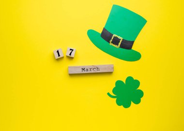 Aziz Patrick Günü kartı. Sarı arka planda yonca ve leprikon şapka. Tahta takvimde 17 Mart tarihi. St. Paddy Günü konsepti