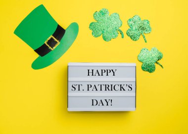 Aziz Patrick Günü konsepti. Sarı arka planda Shamrocks ve leprikon şapka.