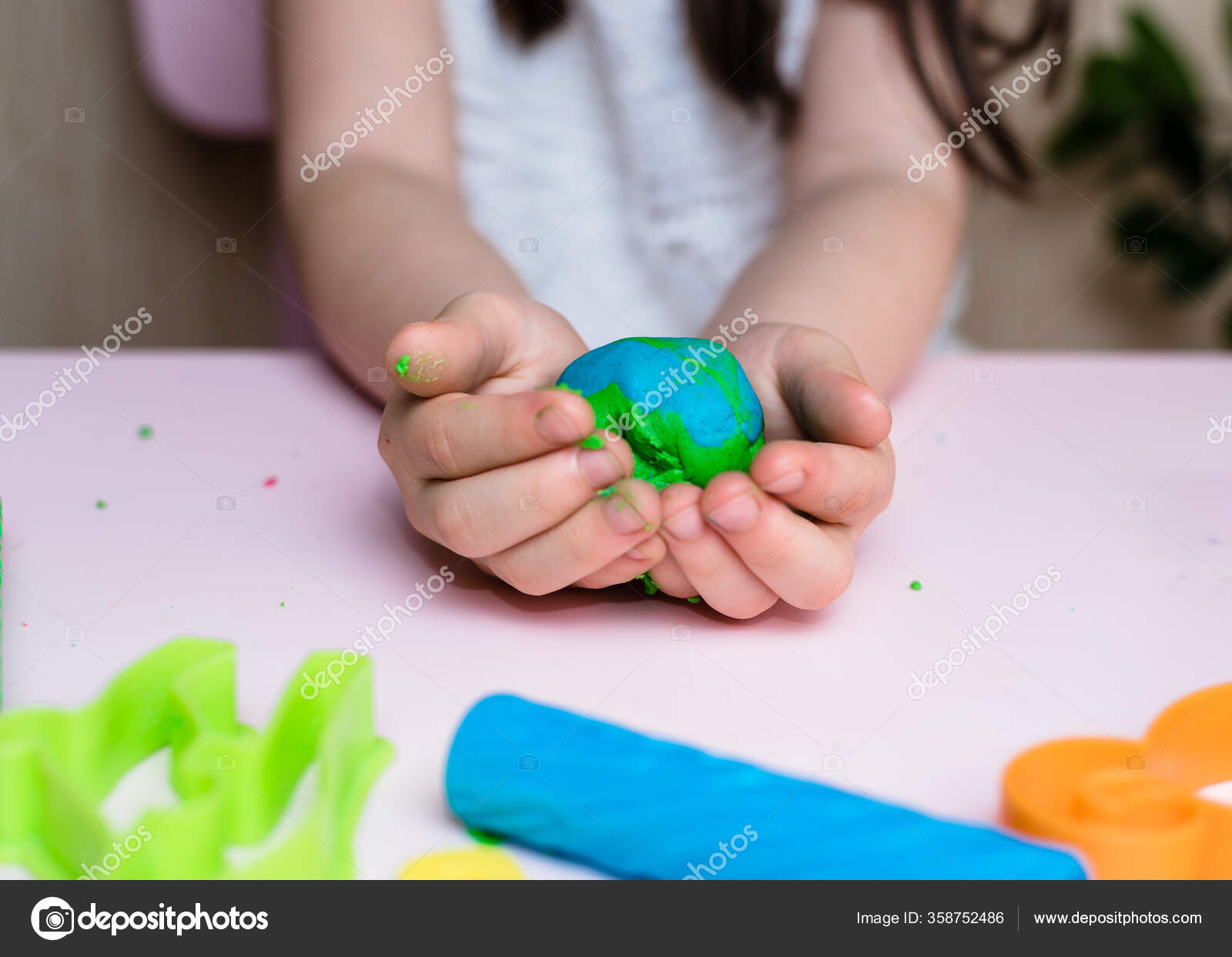 Child hands playing with colorful clay. Homemade plastiline. Plasticine.  play dough. Girl molding modeling clay. Homemade clay. Stock Photo