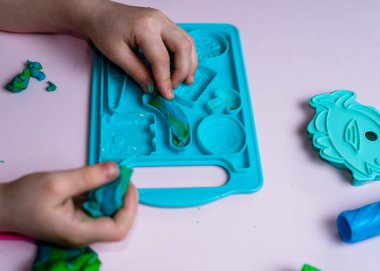 Çocuk elleri renkli kille oynuyor. Ev yapımı plastik. Plastiksin. Hamur oyna. Kil kalıbı yapan kız. Ev yapımı kil.