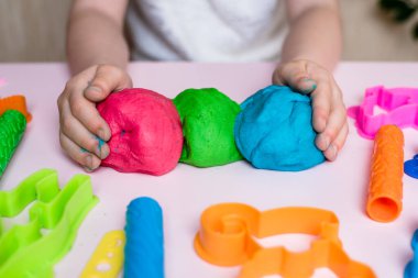 Çocuk elleri renkli kille oynuyor. Ev yapımı plastik. Plastiksin. Hamur oyna. Kil kalıbı yapan kız. Ev yapımı kil.