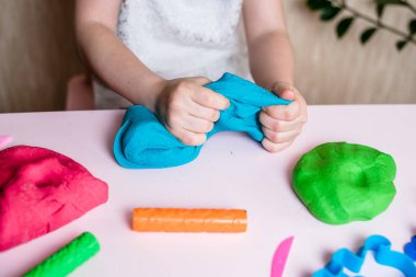 Çocuk elleri renkli kille oynuyor. Ev yapımı plastik. Plastiksin. Hamur oyna. Kil kalıbı yapan kız. Ev yapımı kil.