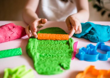 Çocuk elleri renkli kille oynuyor. Ev yapımı plastik. Plastiksin. Hamur oyna. Kil kalıbı yapan kız. Ev yapımı kil.