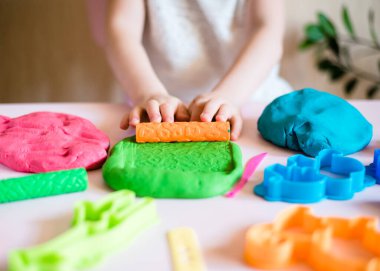 Çocuk elleri renkli kille oynuyor. Ev yapımı plastik. Plastiksin. Hamur oyna. Kil kalıbı yapan kız. Ev yapımı kil.