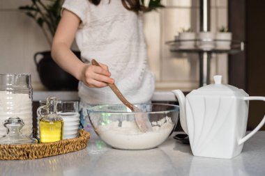 Anaokulundan bir kız un, tuz, ayçiçeği yağı ve mavi gıda boyasından ev yapımı plasticin hazırlıyor. Çocuk elleri renkli kille oynuyor. Ev yapımı plastik. Plastiksin. Hamur oyna. Kil kalıbı yapan kız. Ev yapımı kil.