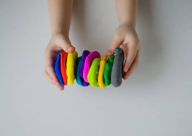 Child hands playing with colorful clay. Homemade plastiline clipart
