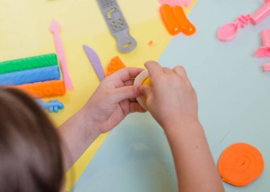 Çocuk elleri renkli kille oynuyor. Ev yapımı plastik.