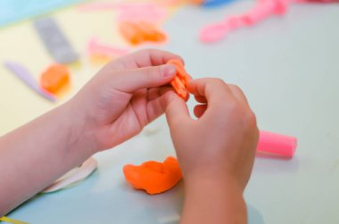 Çocuk elleri renkli kille oynuyor. Ev yapımı plastik.