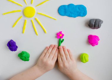 Child hands playing with colorful clay. Homemade plastiline clipart