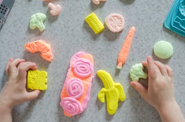 Küçük kız renkli kille oynuyor. Ev yapımı plastik. Plastiksin. Hamur oyna. Kil kalıbı yapan kız. Ev yapımı kil.