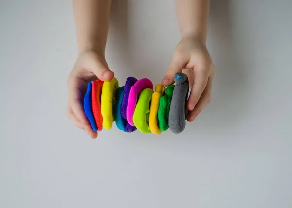 Çocuk elleri renkli kille oynuyor. Ev yapımı plastik.