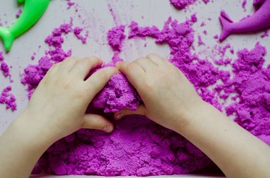 Anaokulu öğrencisi kız evde kinestetik kum yontuyor. Çocuklar için etkinlik geliştirme. Sanat terapisi. Çocuklar için psikoloji terapisi.