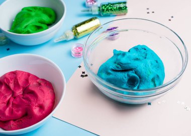 Homemade plasticine, plasticine, play dough on a colored background with glitters. Molding clay or slime. Homemade clay. clipart