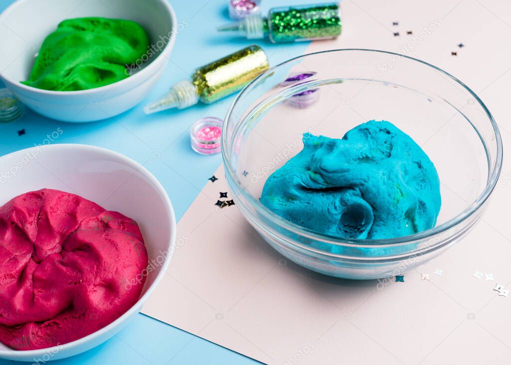 Homemade plasticine, plasticine, play dough on a colored background with glitters. Molding clay or slime. Homemade clay.
