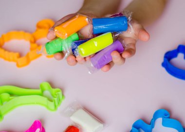 Çocuk elleri renkli kille oynuyor. Plastiksin. Hamur oyna. Kil biçimlendiren kız.