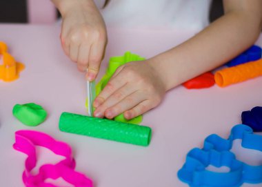 Çocuk elleri renkli kille oynuyor. Ev yapımı plastik. Kil kalıbı yapan kız. Ev yapımı kil. Çocuk oyun oynuyor ve oyun hamurundan yaratıyor. 