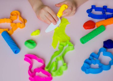 Çocuk elleri renkli kille oynuyor. Ev yapımı plastik. Kil kalıbı yapan kız. Ev yapımı kil. Çocuk oyun oynuyor ve oyun hamurundan yaratıyor. 