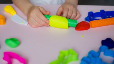 Çocuk elleri renkli kille oynuyor. Ev yapımı plastik. Kil kalıbı yapan kız. Ev yapımı kil. Çocuk oyun oynuyor ve oyun hamurundan yaratıyor. 