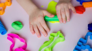 Çocuk elleri renkli kille oynuyor. Ev yapımı plastik. Kil kalıbı yapan kız. Ev yapımı kil. Çocuk oyun oynuyor ve oyun hamurundan yaratıyor. 