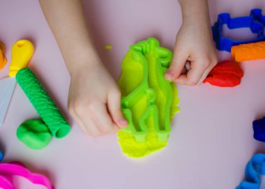 Çocuk elleri renkli kille oynuyor. Ev yapımı plastik. Kil kalıbı yapan kız. Ev yapımı kil. Çocuk oyun oynuyor ve oyun hamurundan yaratıyor. 