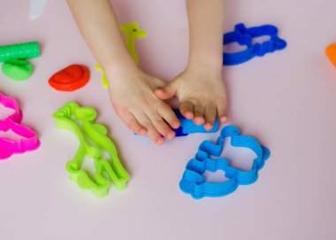 Çocuk elleri renkli kille oynuyor. Ev yapımı plastik. Kil kalıbı yapan kız. Ev yapımı kil. Çocuk oyun oynuyor ve oyun hamurundan yaratıyor. 