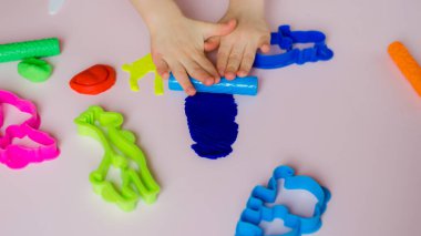 Çocuk elleri renkli kille oynuyor. Ev yapımı plastik. Kil kalıbı yapan kız. Ev yapımı kil. Çocuk oyun oynuyor ve oyun hamurundan yaratıyor. 