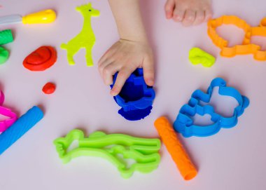 Çocuk elleri renkli kille oynuyor. Ev yapımı plastik. Kil kalıbı yapan kız. Ev yapımı kil. Çocuk oyun oynuyor ve oyun hamurundan yaratıyor. 
