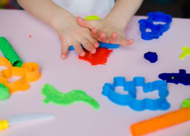 Çocuk elleri renkli kille oynuyor. Ev yapımı plastik. Kil kalıbı yapan kız. Ev yapımı kil. Çocuk oyun oynuyor ve oyun hamurundan yaratıyor. 
