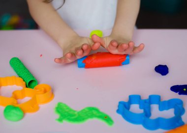 Çocuk elleri renkli kille oynuyor. Ev yapımı plastik. Kil kalıbı yapan kız. Ev yapımı kil. Çocuk oyun oynuyor ve oyun hamurundan yaratıyor. 