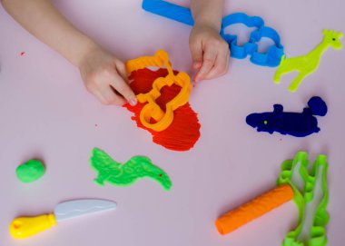 Çocuk elleri renkli kille oynuyor. Ev yapımı plastik. Kil kalıbı yapan kız. Ev yapımı kil. Çocuk oyun oynuyor ve oyun hamurundan yaratıyor. 